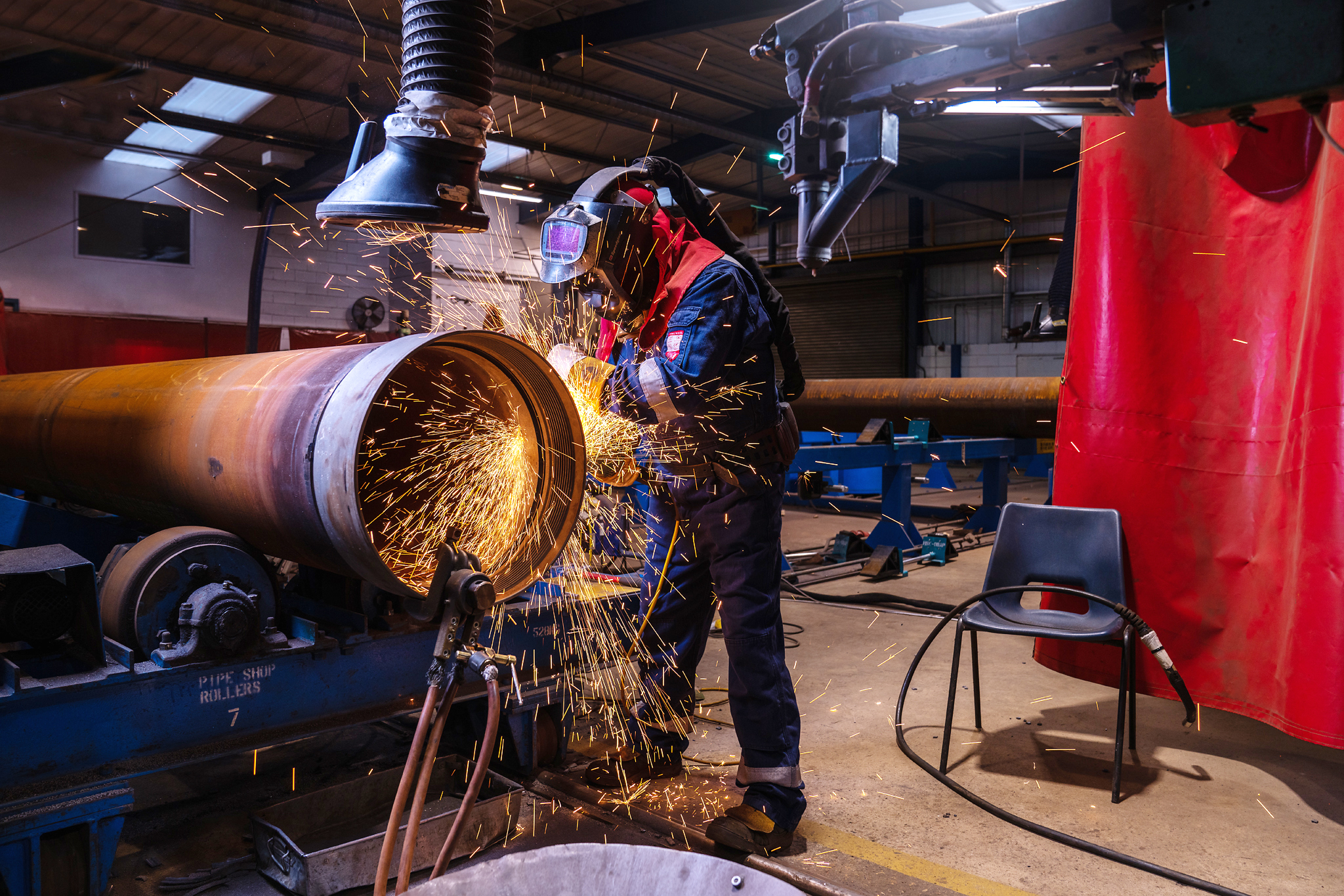 Technician cutting large steel component with sparks