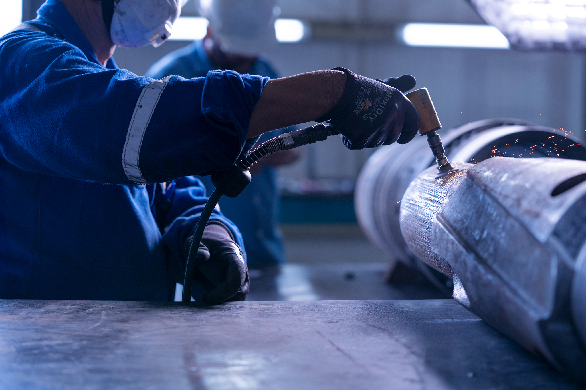 Technician preparing surface of large metal component